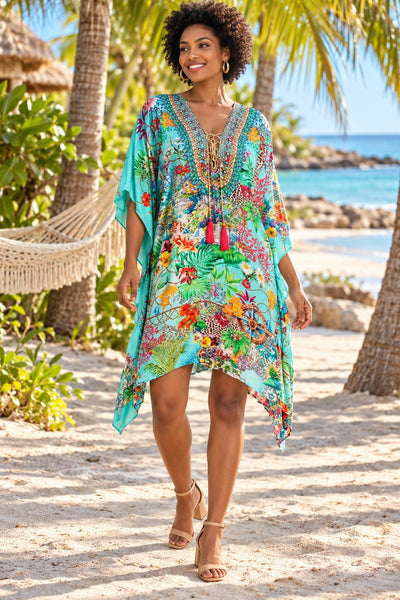 Turquoise tropical print kaftan with embellished lace-up V-neck and tassels, front view in Caribbean palm grove - wholesale resort kaftans