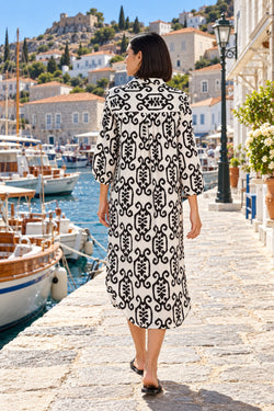 Back view of black and white ikat three-quarter sleeve shirt dress with yoke walking along a stone quay - La Moda vacation dress